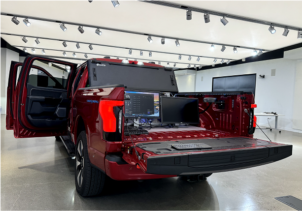 A production truck with its tailgate down, set up as a mobile prototyping station with monitors and a keyboard running the platform